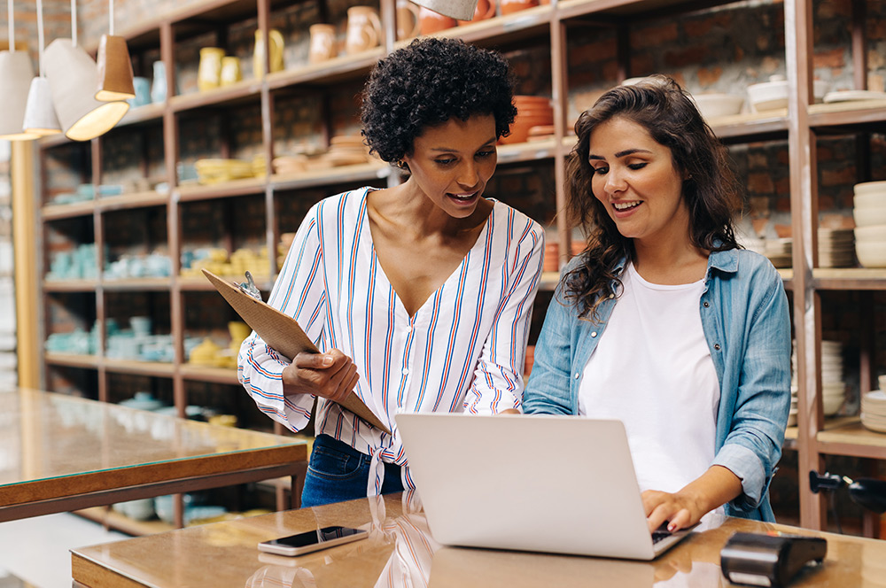 Two business women reviewing finances on laptop