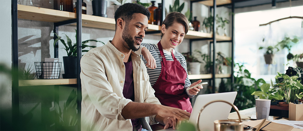 Two small business owners looking at laptop reviewing finances