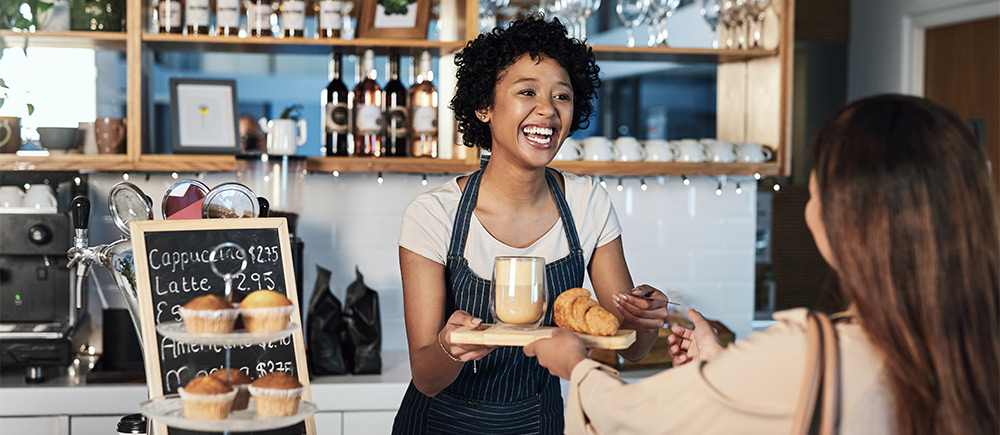 Smiling woman serving food to customer at café 