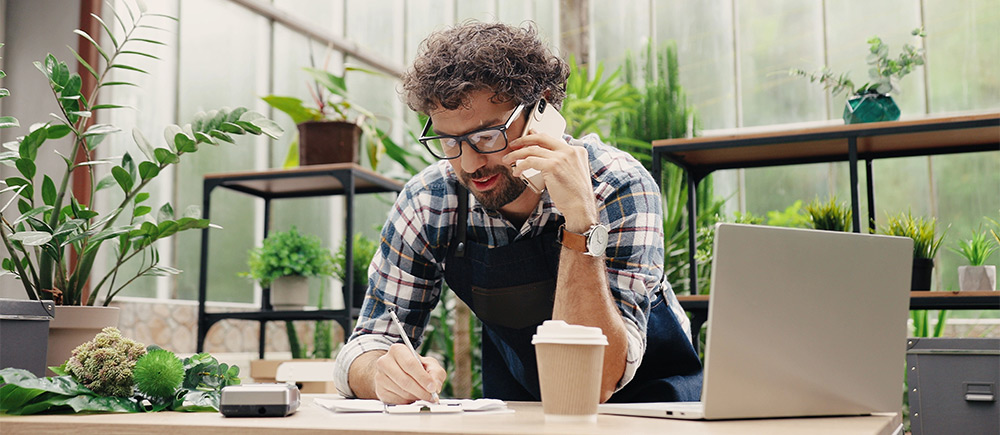 Retail business owner on phone writing notes