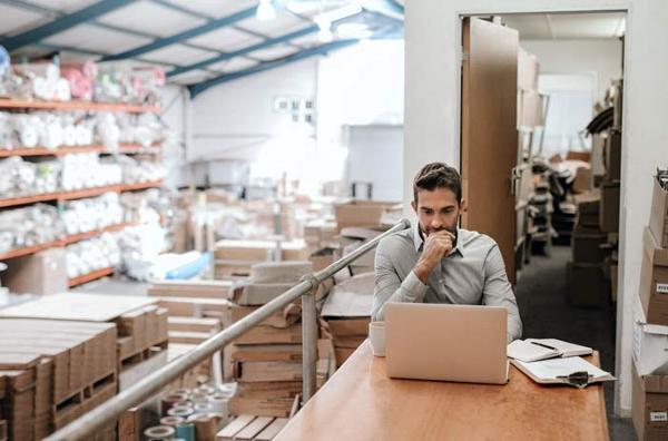 A business owner on a laptop in a warehouse